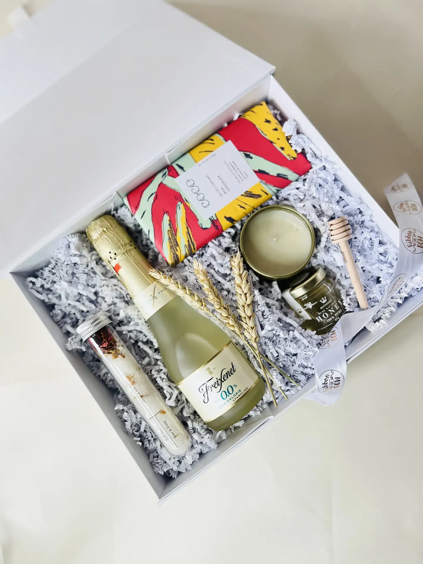 Curated gift box with sparkling wine, candle, honey and art card